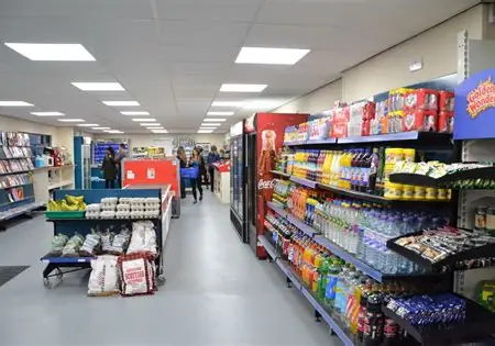Inside the shop, looking down a well-stocked aisle of groceries and drinks