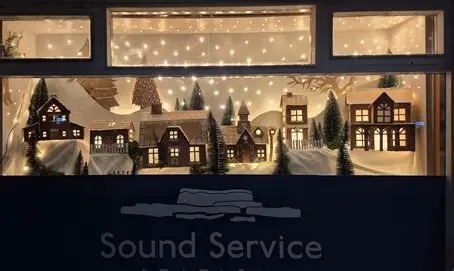 The shop's lit Christmas window display of miniature snow-covered houses